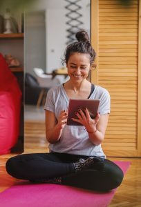 woman taking online yoga classes on tablet