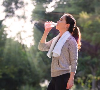 Sporty woman drinking water outdoor on sunny day