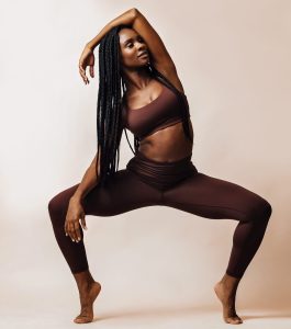 image of beautiful black woman with braids in a balancing pose, stupa or goddess pose demonstrating how her balance has improved with online yoga classes