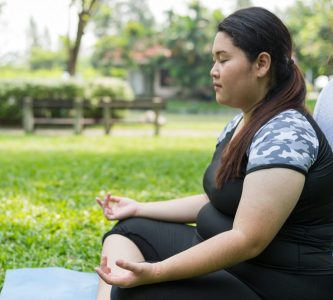 curvy woman meditating in park as act of self-care